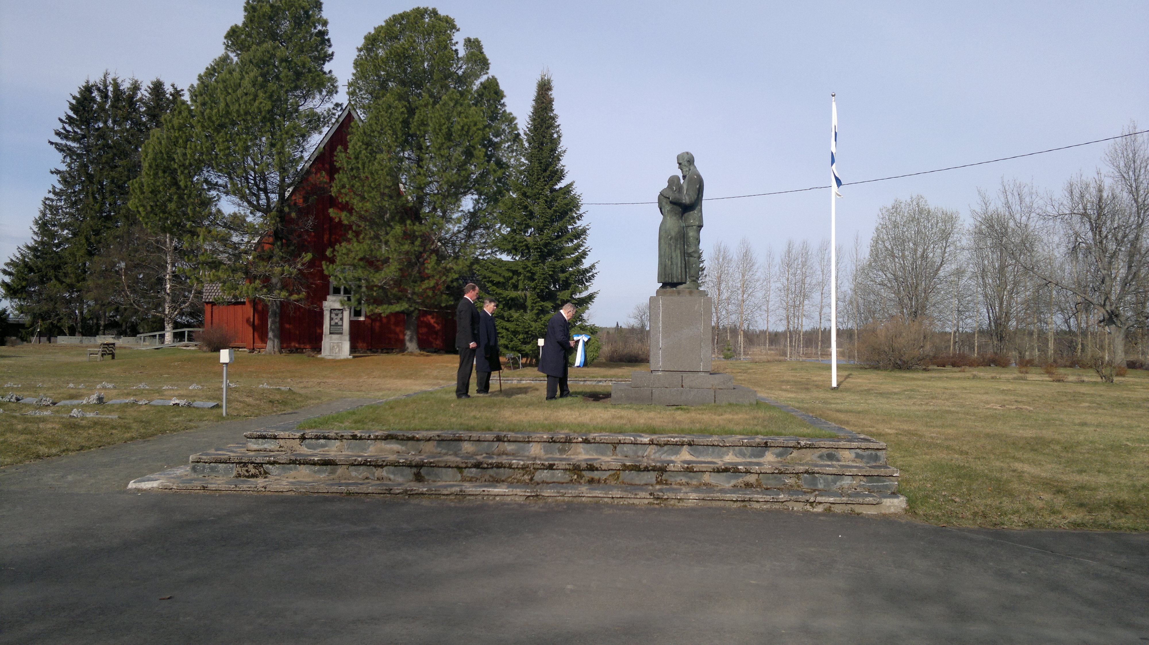 Kaatuneiden muistopäivän kunniakäynti Kuvassa veteraani laskee seppelettä sankarihaudalle kahden henkilön seistessä taustalla.